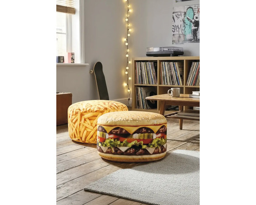 Twee ronde vloerkussens met hamburger- en patatmotief in een lichte woonkamer op een houten vloer naast een kast.