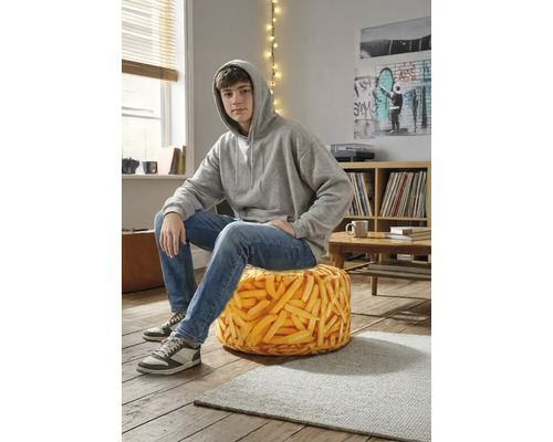 Tiener zit op een ronde zitzak met een realistische patatprint in een modern ingerichte kamer met houten vloer.