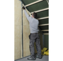 Vakman bij het installeren van minerale wol voor isolatie tussen een muur en een schuin dak.