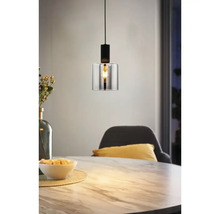 Moderne hanglamp met een cilindrische glazen kap en een zwart metalen armatuur boven een eettafel met marmerlook.