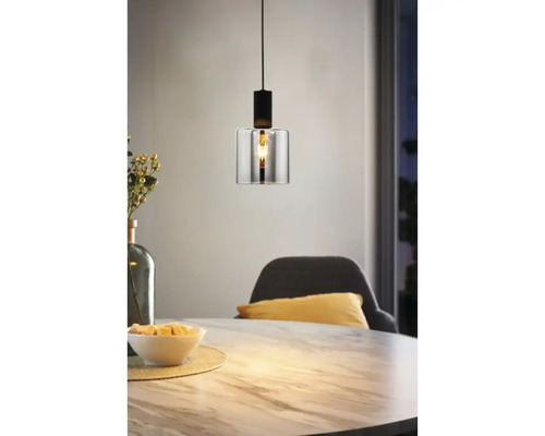 Moderne hanglamp met een cilindrische glazen kap en een zwart metalen armatuur boven een eettafel met marmerlook.