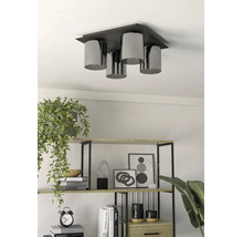 Moderne 4-lichts plafondlamp met cilindrische kappen boven een rek met decoratie en planten.
