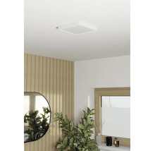 Vierkante LED-plafondlamp aan wit plafond in moderne kamer met houten wandpanelen, spiegel en groene plant.