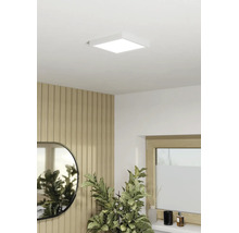 Vierkant LED-paneel als plafondlamp in een modern ingerichte kamer met houten lattenwand, spiegel en kamerplant.