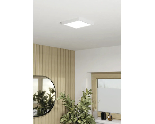 Vierkant LED-paneel als plafondlamp in een modern ingerichte kamer met houten lattenwand, spiegel en kamerplant.