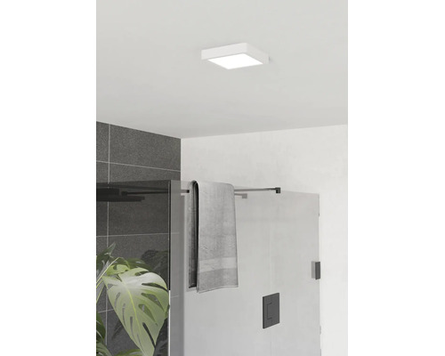 Vierkante LED-plafondlamp in een moderne badkamer boven een glazen douchewand met zwart beslag en donkergrijze wandtegels.