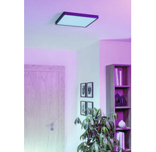 Vierkant LED-plafondpaneel in een woonkamer met plank, deur en kamerplant, voor sfeervolle kamerverlichting.