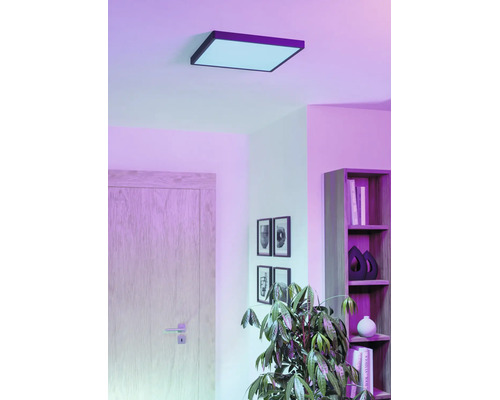 Vierkant LED-plafondpaneel in een woonkamer met plank, deur en kamerplant, voor sfeervolle kamerverlichting.