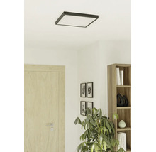 Vierkante LED-plafondlamp met donker frame in een lichte, moderne kamer met houten deur, boekenkast en kamerplant.