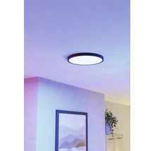 Ronde LED plafondlamp met een zwart frame in een modern ingerichte kamer met paars licht en een schilderij aan de wand.