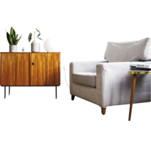 Woonkamerinrichting met een houten dressoir, een lichtgrijze fauteuil, een bijzettafel, kamerplanten en een witte bolvormige lamp.