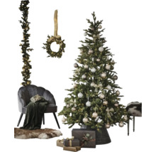 Feestelijk versierde kerstboom in mand, grijze fluwelen fauteuil met deken, bontkleed, cadeaus en een krans en guirlande aan de muur.