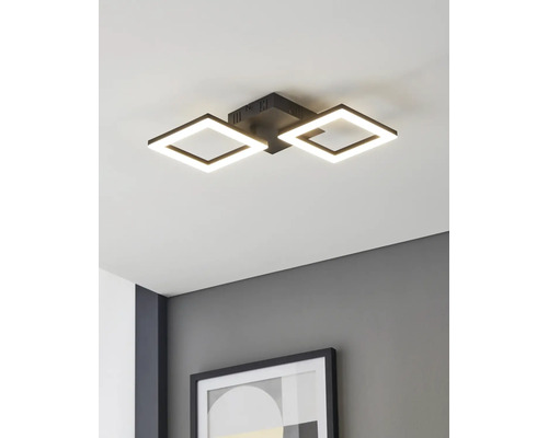 Moderne LED-plafondlamp met twee vierkante zwarte frames, gemonteerd aan een wit plafond boven een grijze muur met een ingelijste foto.