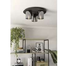 Moderne plafondlamp met metalen voet en glazen kappen in een lichte kamer met een decoratieve plank en kamerplanten.