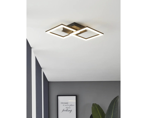 Moderne zwarte LED-plafondlamp met twee in elkaar grijpende vierkante lichtframes in een modern ingerichte kamer.