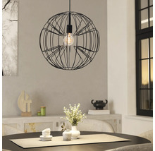 Bolvormige hanglamp van zwart draadgaas boven een ronde eettafel in een lichte, modern ingerichte kamer.