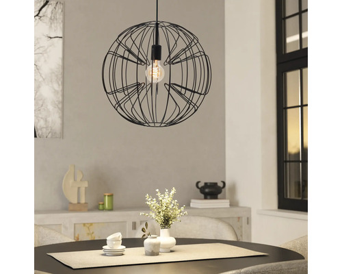 Bolvormige hanglamp van zwart draadgaas boven een ronde eettafel in een lichte, modern ingerichte kamer.