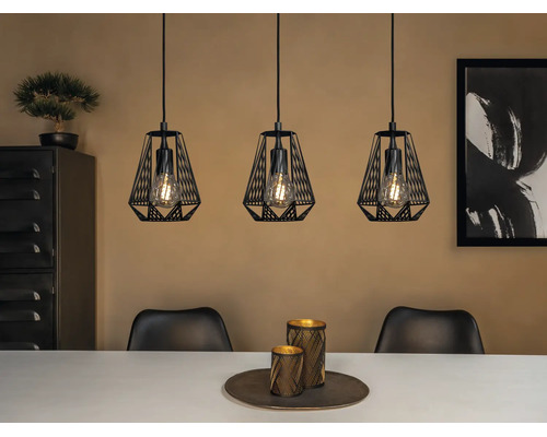 Drievlammige hanglamp met zwarte metalen draadkappen en zichtbare lichtbronnen boven een eettafel in een modern interieur.