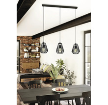 Drielamps hanglamp in industrieel design met zwarte metalen kooikappen boven een eettafel in een lichte, modern ingerichte kamer.