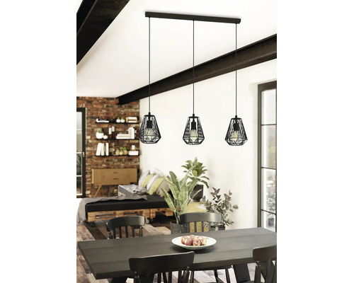 Drielamps hanglamp in industrieel design met zwarte metalen kooikappen boven een eettafel in een lichte, modern ingerichte kamer.