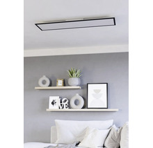 Moderne rechthoekige LED-plafondlamp met zwart frame gemonteerd boven wandplanken in een lichte woonkamer.