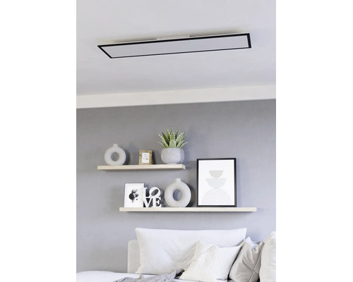 Moderne rechthoekige LED-plafondlamp met zwart frame gemonteerd boven wandplanken in een lichte woonkamer.