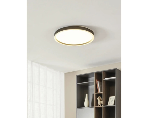 Moderne, ronde LED-plafondlamp in een minimalistisch interieur boven een donkergrijze plank.