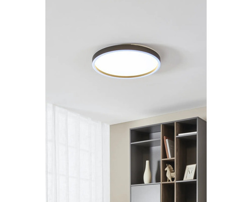 Moderne ronde LED-plafondlamp in een licht, georganiseerd interieur met een kast en gordijn.