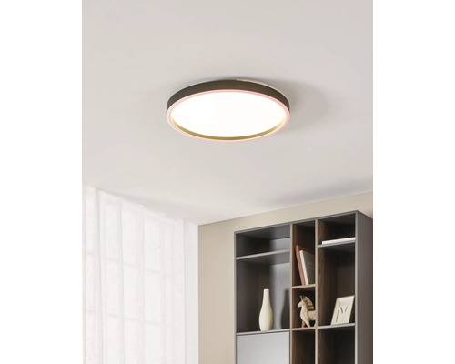 Moderne, ronde LED-plafondlamp met warmwit licht en een gekleurde rand aan een plafond in een lichte, georganiseerde kamer met een kast.