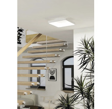Vierkante LED-plafondlamp in een lichte, moderne woonruimte met een open houten trap en kamerplanten.