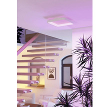 Vierkante LED-plafondlamp in een lichte, modern ingerichte woonkamer met houten trap en glazen leuning.