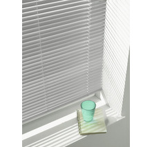 Jaloezie met horizontale lamellen voor een raam, die schaduwen werpt op een vensterbank met een glas en een notitieblok.