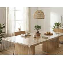 Transparante tafelzeil op een lichte houten tafel in een lichte, georganiseerde eetkamer met een gevlochten lamp en een bonsai.