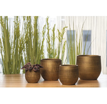 Vier decoratieve bloempotten in verschillende maten van metaal met een gestructureerd oppervlak op een houten tafel voor planten.