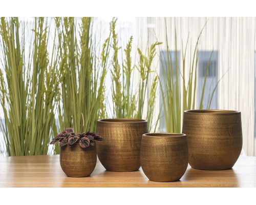 Vier decoratieve bloempotten in verschillende maten van metaal met een gestructureerd oppervlak op een houten tafel voor planten.