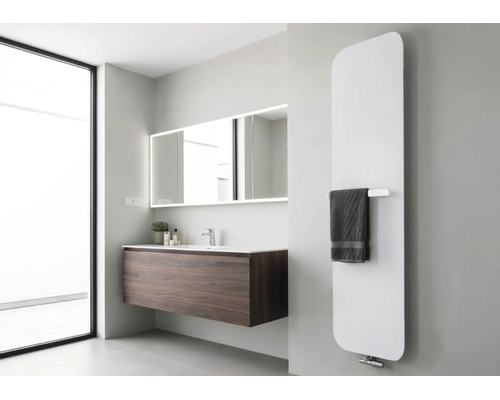 Moderne verticale designradiator in een lichte badkamer met donker wastafelmeubel en verlichte spiegel.