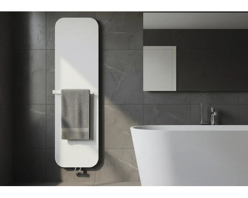 Moderne witte badkamerradiator met afgeronde hoeken en handdoekhouder, gemonteerd op donkergrijze marmeren tegels naast een badkuip.
