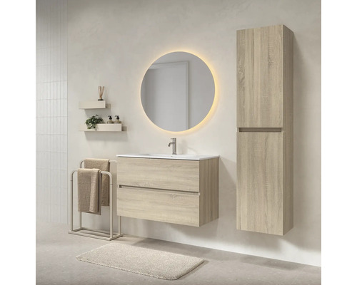 Moderne badkamerset met wastafelmeubel in lichte houtlook, wastafel, ronde verlichte spiegel en bijpassende hoge kast.