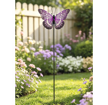 Tuinsteker met een paars en wit gedessineerde vlinder, geplaatst in een lichte tuin met bloemen en een houten hek.