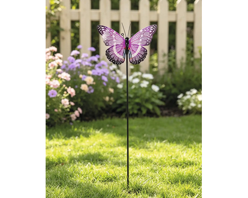 Tuinsteker met een paarse vlinder op een gazon voor bloemen en een licht houten hek.