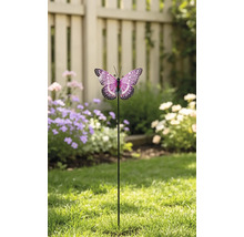 Decoratieve tuinsteker vlinder met gedetailleerde vleugels op een metalen staaf, geplaatst op een gazon voor een schutting en bloemen.