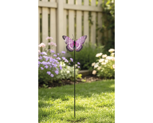 Decoratieve tuinsteker vlinder met gedetailleerde vleugels op een metalen staaf, geplaatst op een gazon voor een schutting en bloemen.