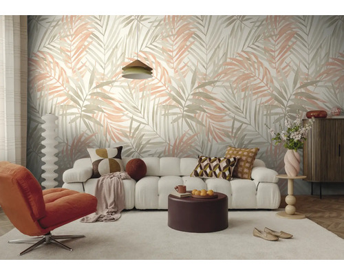 Moderne woonkamer met vliesbehang met palmbladmotief, een witte bank, een oranje fauteuil en een ronde salontafel.