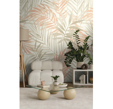 Moderne woonkamer met palmbladbehang, witte bouclé fauteuil, glazen salontafel en groene kamerplant.