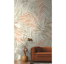 Vliesbehang met een groot patroon van palmbladeren in aquarelstijl in een woonkamer met een oranje bank.