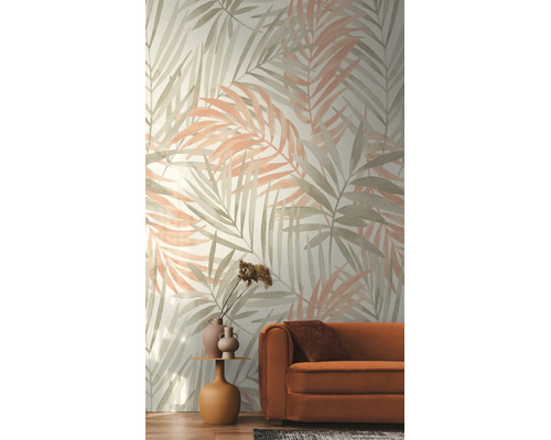 Vliesbehang met een groot patroon van palmbladeren in aquarelstijl in een woonkamer met een oranje bank.