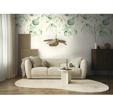Fotobehang met eucalyptusmotief in aquarelstijl boven een beige bank in een lichte, modern ingerichte woonkamer met licht tapijt.