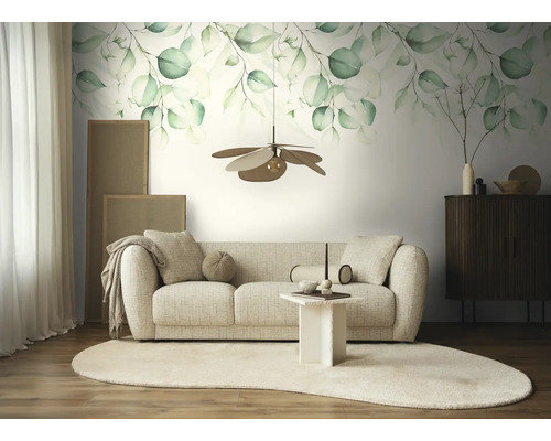 Fotobehang met eucalyptusmotief in aquarelstijl boven een beige bank in een lichte, modern ingerichte woonkamer met licht tapijt.