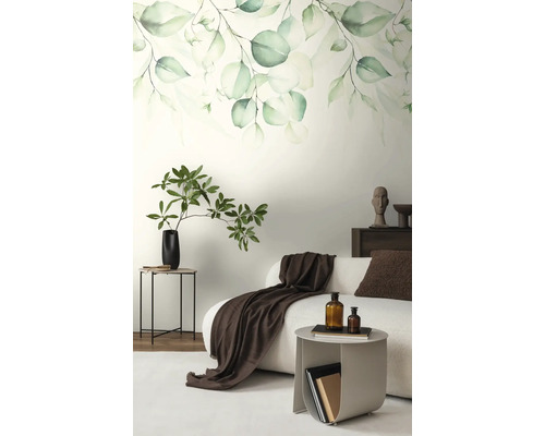 Fotobehang met eucalyptusbladeren in aquarelstijl in een modern ingerichte woonkamer met witte bank en bruine accenten.