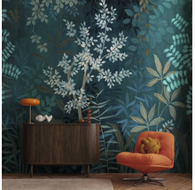 Vliesbehang met botanisch bladerpatroon in donkergroen en blauw, gecombineerd met een donker dressoir en een oranje fauteuil.